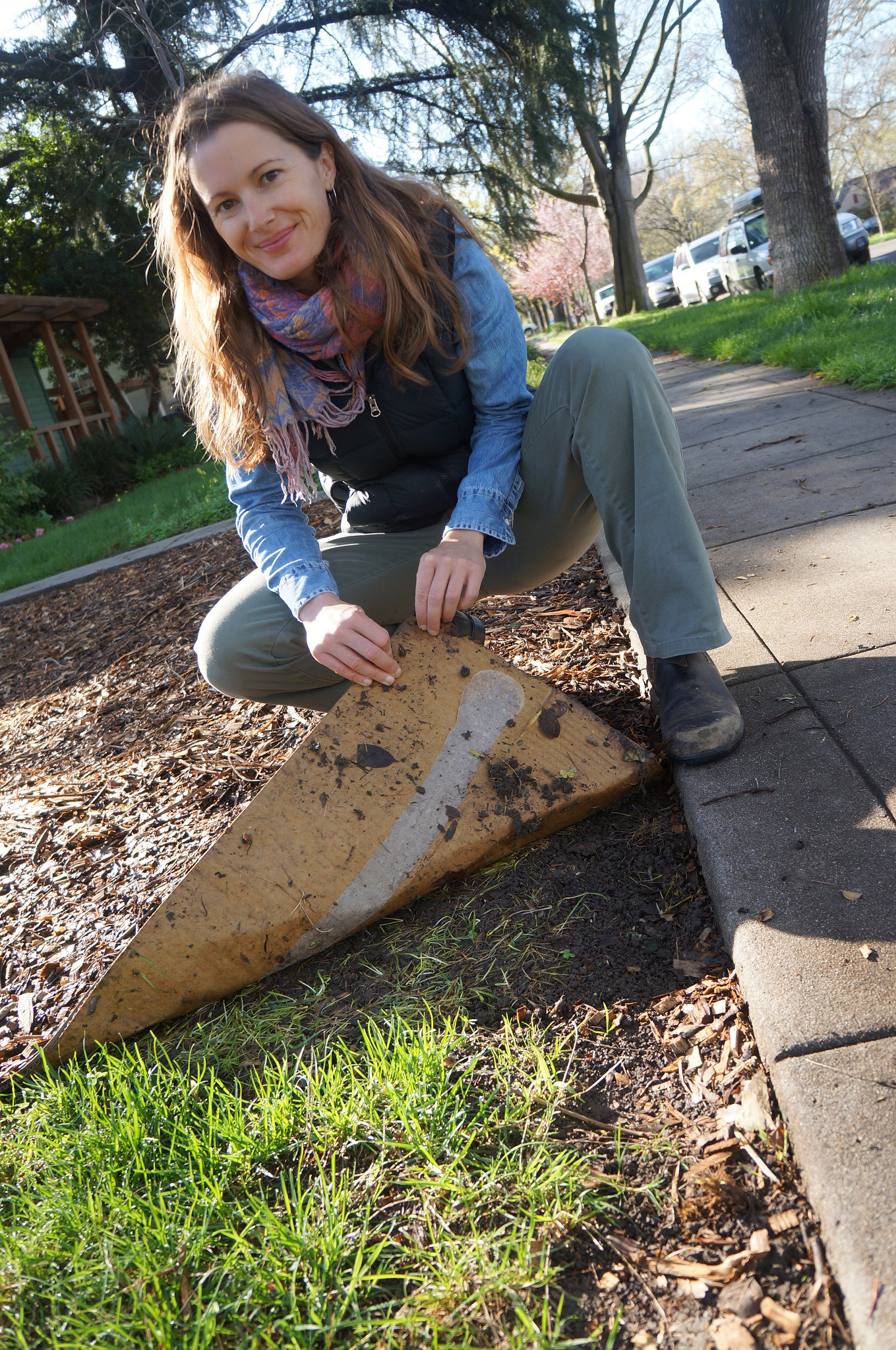Image of Stacey Parker lifting up cardboard to reveal a lawn free patch.
