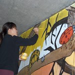 Image of student painting the original A Street Bridge mural in the UC Davis Arboretum.