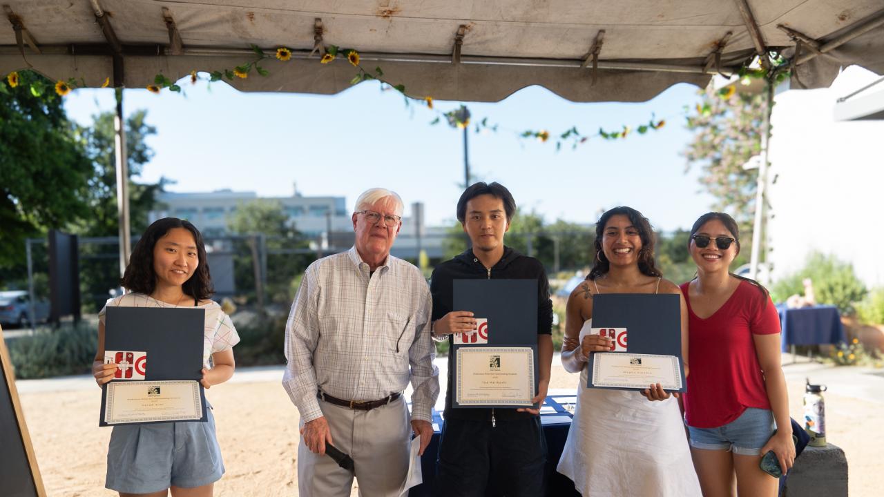 Three interns pose with certificates next to Bret Hewitt