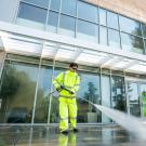 Person using a pressure washer outside the Watershed Sciences building