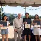 Three interns pose with certificates next to Bret Hewitt